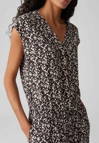 Top a righe in bianco e nero con scollatura a V, maniche corte e vita elastica, realizzato in tessuto leggero.