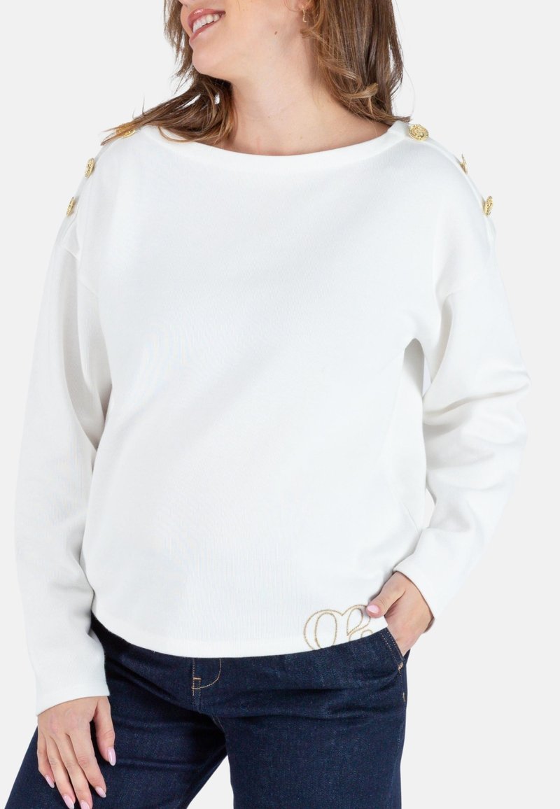 Weißes Sweatshirt mit langen Ärmeln und Bootsausschnitt, ausgestattet mit goldenen Knopfakzenten an den Schultern und einem strukturierten Stoff. Dekorative Nähte am Saum.