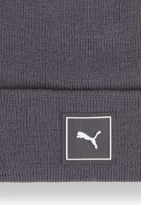 Grå strikket hue med et tekstureret design og et firkantet logo-patch med en hvid springende puma på sort baggrund.