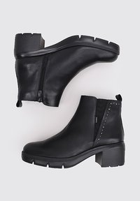 Botas de cuero negro hasta el tobillo con cremallera lateral, acabado texturizado, tacón bloque y tachuelas que acentúan un lado. Punta redondeada y suela resistente.