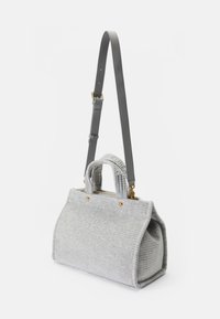 Bolsa de tecido cinza com uma forma estruturada. Apresenta duas alças curtas, uma correia cinza ajustável e detalhes em metal dourado. Superfície texturada.