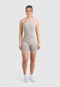 Set atletico grigio chiaro in tessuto morbido, composto da un top corto con spalline sottili e pantaloni corti a vita alta; texture liscia, design senza cuciture.