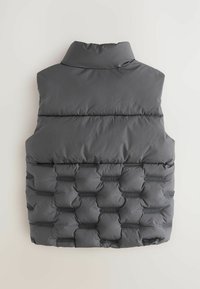 Gilet rembourré gris avec un col montant et un design matelassé, comprenant un détail de marque. Le matériau semble doux avec une surface texturée.
