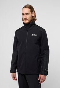 Giacca in pile nera con maniche lucide a contrasto, chiusura con zip, collo alto e logo sul petto. Presenta tasche laterali e polsini regolabili.