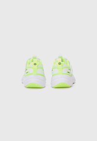 Des chaussures de sport en néon jaune et blanc présentent un dessus en maille respirante, une semelle rembourrée et une languette à l'arrière pour un enfilage facile.