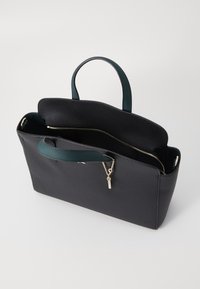 Sac fourre-tout en cuir noir avec une texture granuleuse, présentant deux poignées supérieures en bleu sarcelle, une poche zippée à l'intérieur et des garnitures en ton doré.