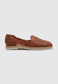 Zapato de cuero trenzado marrón tipo slip-on con lados abiertos, suela plana y acabado texturizado que presenta patrones de trenzado intrincados.