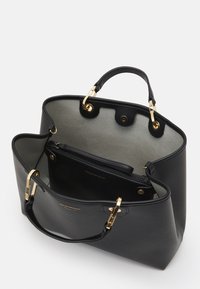 Sac en cuir noir avec quincaillerie dorée, forme structurée et intérieur gris. Il dispose d'une poche zippée et d'une fermeture à pression.