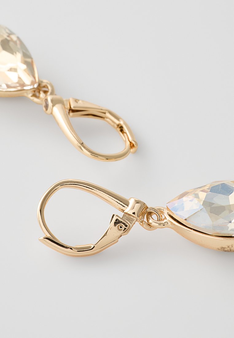 Goldfarbene Tropfohrringe mit tropfenförmigen klaren Strasssteinen mit facettierten Oberflächen, die über sichere Klappverschlüsse befestigt sind.