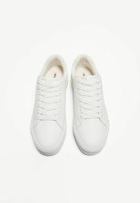 Baskets en cuir blanc avec une finition lisse, dotées de six œillets, de lacets plats et de semelles en caoutchouc texturé pour une meilleure adhérence.