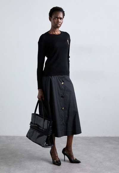 Black ribbed sweater, knee-length black skirt with gold buttons, black patent handbag, and black pointed heels with metallic accents.