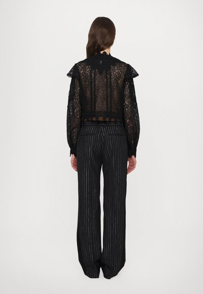 Black lace top with ruffled collar and long sleeves, paired with black pinstriped trousers. Both pieces showcase intricate details and textures.