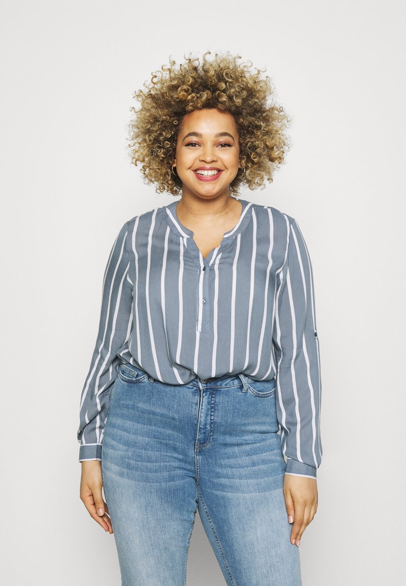 Gray striped blouse with a buttoned placket and long sleeves, paired with light blue high-waisted jeans. Smooth fabric, casual fit.