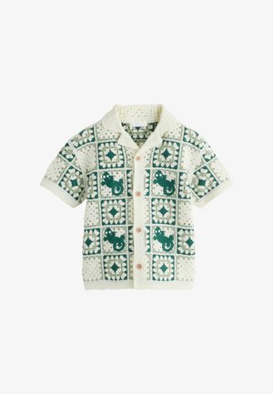 Maglietta in crochet crema a maniche corte con motivi a quadrati verdi e chiusura frontale con bottoni.