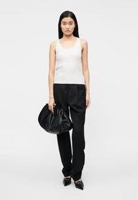 Λευκό ριγέ τοπ, μαύρο ραμμένο παντελόνι και μεγάλη μαύρη τσάντα. Μαύρα μυτερά παπούτσια με γυαλιστερό φινίρισμα. Απλός και καθαρός σχεδιασμός.