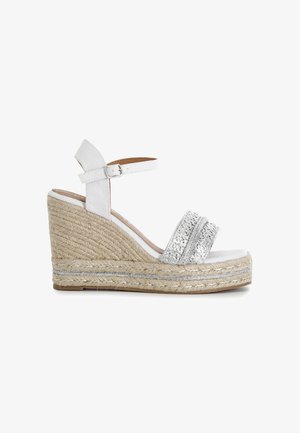 Sandale compensée blanche avec plateforme en jute tressée, bride avant pailletée argentée et bride de cheville réglable avec boucle.