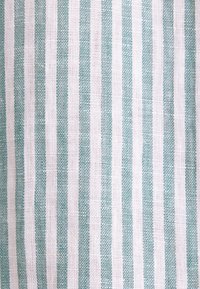 Gros plan sur un tissu à rayures verticales tissées bleu clair et blanches, espacées de manière régulière.