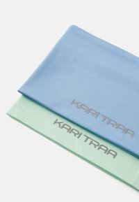 Twee haarbanden in blauw en lichtgroen, gemaakt van zacht ribbelstof, zijn voorzien van het "KARI TRAA" logo in zilver aan de voorkant.