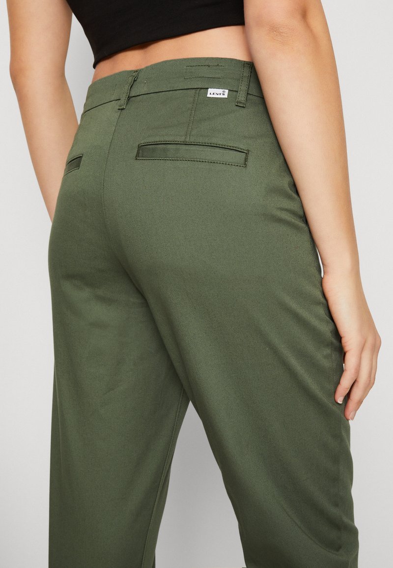 Pantalons verts olive avec une texture lisse, dotés de deux poches arrière et d'une étiquette de logo Levi's à la taille. Coupe ajustée.