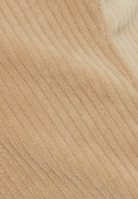 Ribbade tyger i en mjuk beige nyans, med en texturerad design med vertikala linjer. Materialet verkar lyxigt och inbjudande.