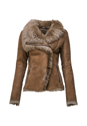 Femme portant une veste marron à col en fourrure, pantalon en cuir noir, chaussures noires, tenant un sac à main à imprimé léopard, debout devant un fond uni.