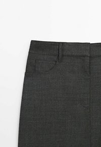 Pantalon en tissu gris foncé montrant la partie supérieure de la taille avec des passants de ceinture, une poche avant et des coutures visibles.