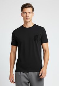 Schwarzes T-Shirt mit kurzen Ärmeln, das über einen strukturierten Taschenaufdruck und einen runden Ausschnitt verfügt. Aus glattem Stoff mit taillierter Silhouette gefertigt.