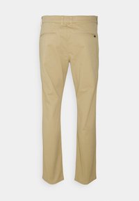 Chino khaki con taglio dritto, caratterizzati da una texture liscia, due tasche posteriori e passanti per la cintura. Branding minimale sulla vita.