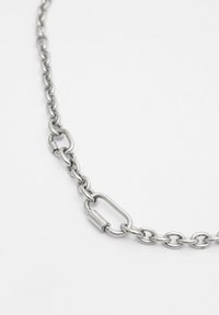 Culoare metalică argintie, un colier cu lanț format din linkuri oval și rotunde interconectate, prezentând un detaliu de închidere și o textură netedă și lustruită.