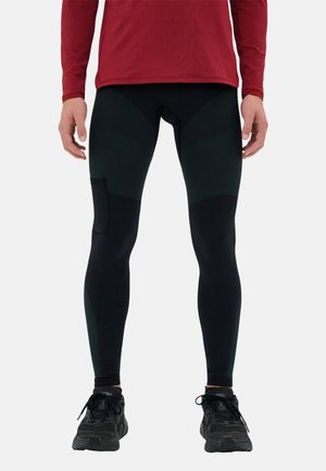 Schwarze Sportleggings mit strukturierten dunkelgrünen Einsätzen und einer Seiten Tasche. Getragen mit einem roten Langarmshirt und schwarzen Laufschuhen.