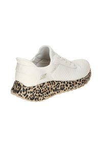 Biały but sportowy z teksturowaną cholewką, z podeszwą w wzór cętki w beżowym kolorze z czarnymi akcentami. Wiązany sznurowadłami.