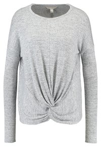 Haut gris à manches longues avec une coupe décontractée, doté d'un nœud sur le devant et d'un tissu texturé à motif chiné subtil.