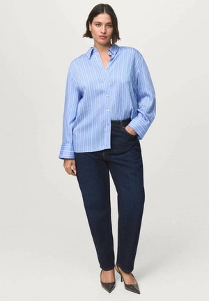 Chemise à rayures bleu clair, à boutons et à manches longues, associée à un jean en denim foncé. La chemise a une coupe décontractée et un col classique.