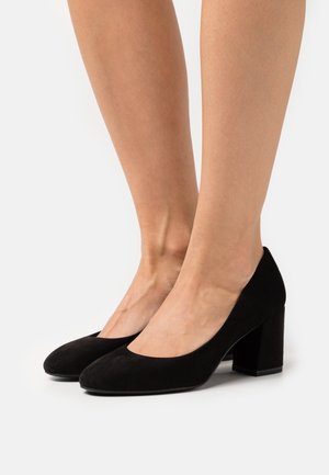 Chaussures à talons hauts en suède noir avec un bout arrondi et un large talon bloc. Texture lisse et design classique et minimal.