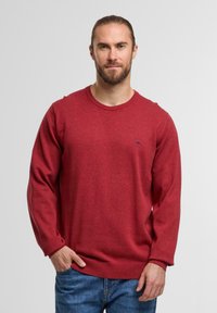 Roter Rundhalspullover aus weichem Stoff, mit langen Ärmeln und einem gerippten Saum sowie einem kleinen Logoakzent auf der Brust.