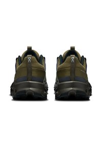 Groene en grijze trailrunschoenen met een gestructureerde mesh bovenkant, stevige zool en een opvallend loopprofiel, met logodetails op de achterkant.