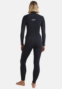 Svart våtdräkt med långa ärmar, slät textur, med ett mönstrat tyg på ärmarna och en logo på baksidan. Åtsittande design.