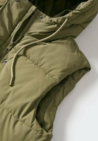 Oliwkowa, bezrękawnikowa kamizelka puchowa z zamkiem z przodu, kapturem ze ściągaczem i wyraźnie zaznaczonymi szwami; wykonana z gładkiej, pikowanej tkaniny.