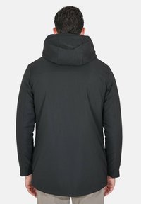 Giacca nera con cappuccio, caratterizzata da una texture liscia e un orlo posteriore leggermente più lungo. Il materiale sembra impermeabile con cuciture minime.