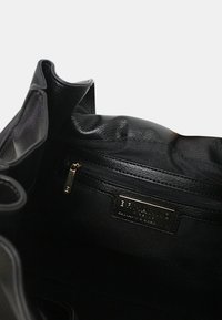 Borsa a tracolla nera realizzata in pelle texture, con una tasca con zip e un'etichetta del marchio. L'interno è foderato e spazioso, con bordi morbidi.
