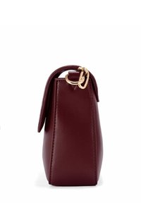 Bordowa skórzana torebka z boku z złotymi klamrami na białym tle.