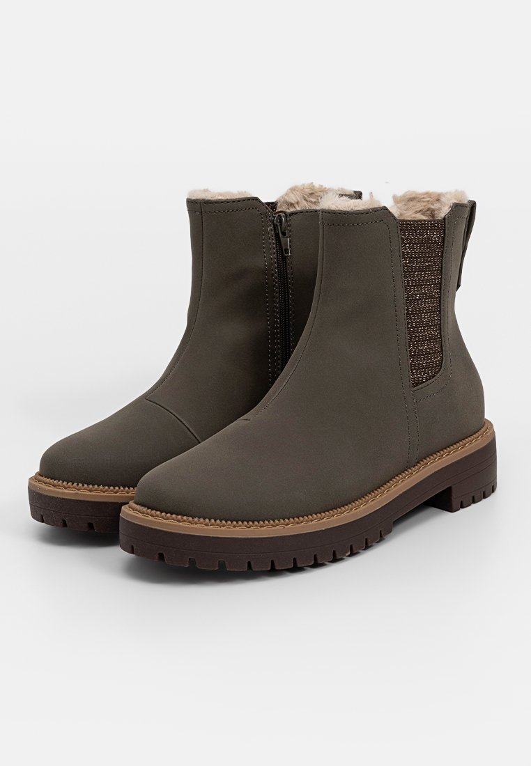 Donkergroene enkellaarsjes met nepbontvoering, elastische zijkanten en een gestructureerd detail. Dikke bruine rubberen zool voor betere grip.