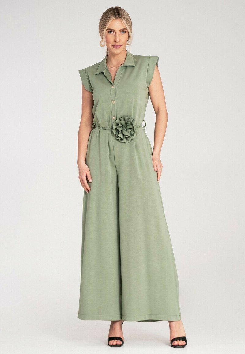 Zielony kombinezon bez rękawów z kołnierzykiem, guzikami z przodu, szerokimi nogawkami oraz tkaninowym kwiatem na talii. Gładka tekstura i casualowy design.