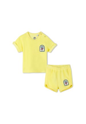 Geel katoenen twee-delig setje met een shirt met korte mouwen en opgerolde mouwen en een logo-patch, en bijpassende shorts met een elastische tailleband.