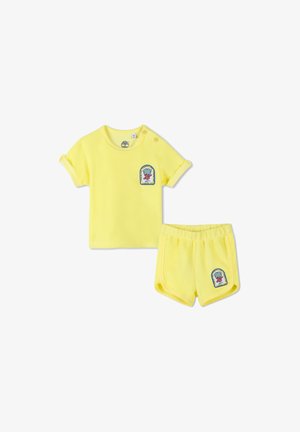 Geel katoenen twee-delig setje met een shirt met korte mouwen en opgerolde mouwen en een logo-patch, en bijpassende shorts met een elastische tailleband.