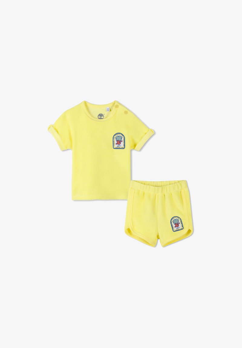 Gelbes Baumwoll-Zweiteiler-Outfit mit einem kurzärmeligen Hemd mit gekrempelten Ärmelenden und Logo-Patch sowie passenden Shorts mit elastischem Bund.