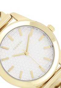 Montre-bracelet dorée avec un cadran argenté texturé, des index et des aiguilles dorés. Présente un boîtier rond et une couronne avec une finition polie.
