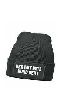 Black knit beanie with ribbed texture and a folded cuff. Features a rectangular patch with white text: “DER MIT DEM HUND GEHT.”