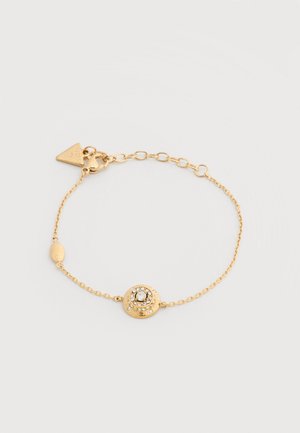 Delicate gold chain bracelet with a round, crystal-embellished charm and a triangular clasp tag on a white background.