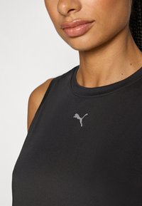 Svart träningslinne i slätt tyg, med rund halsringning och en liten grå Puma-logga på bröstet.
